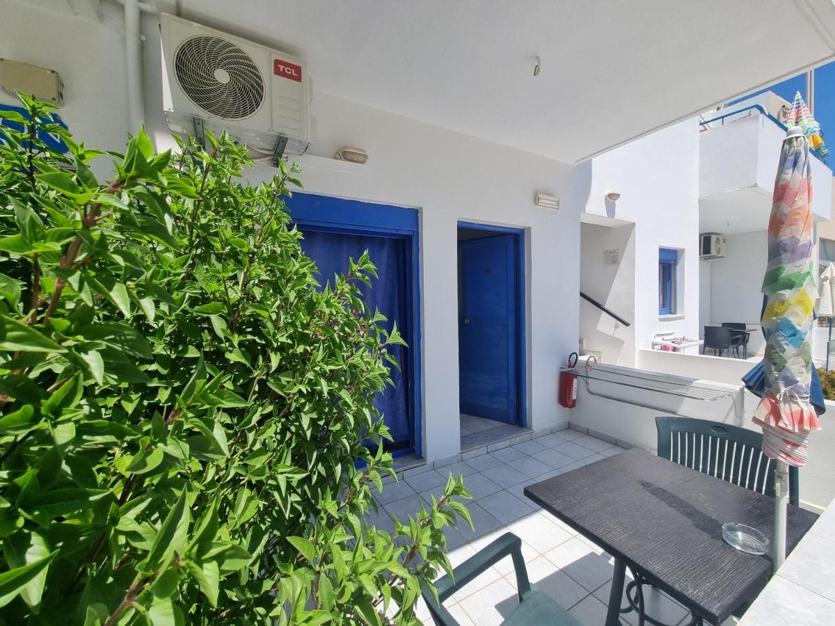 een klein balkon met een tafel en een blauwe deur bij Leonidas Studios & Apartments in Georgioupolis