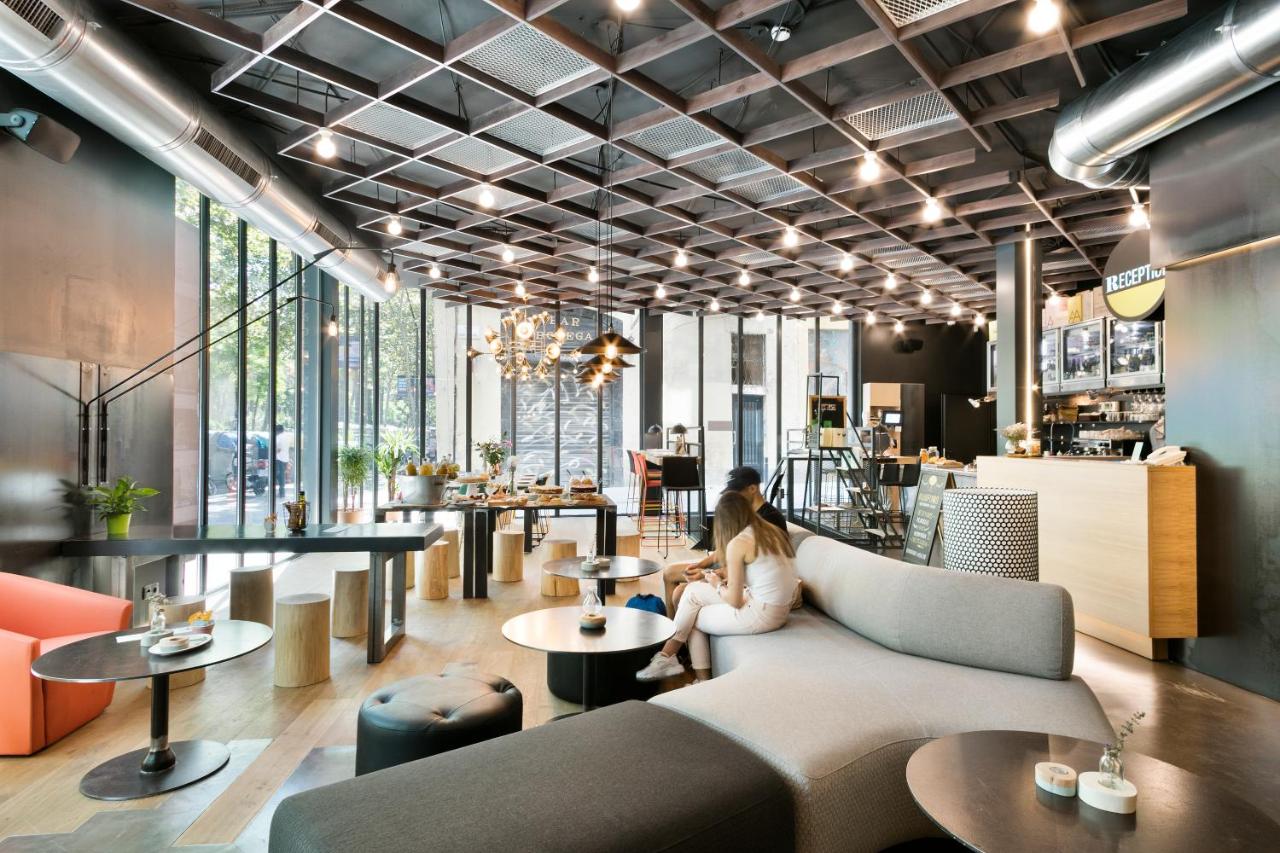 een vrouw die op een bank in een restaurant zit bij Niu Barcelona Hotel in Barcelona