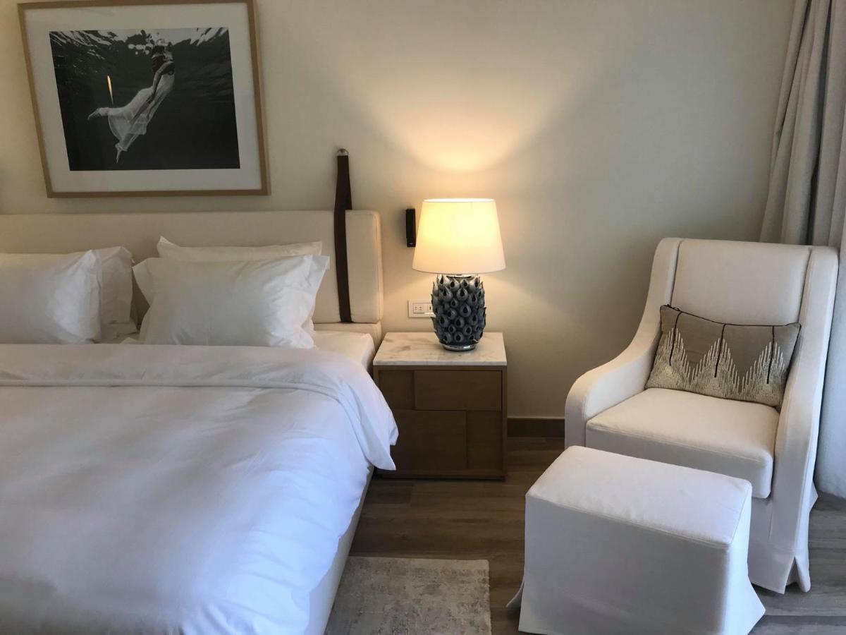 een slaapkamer met een bed, een stoel en een lamp bij Domes Miramare, a Luxury Collection Resort, Corfu - Adults Only in