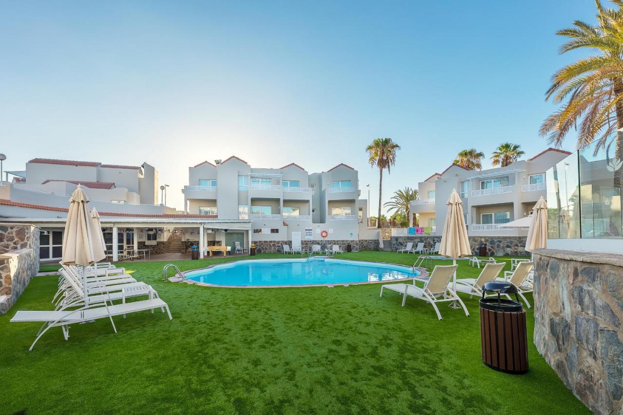 een resorttuin met stoelen en een zwembad bij Apartamentos LIVVO Koala Garden in Maspalomas +28 foto's