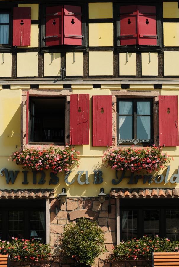 een gebouw met ramen met rode luiken en bloembakken bij Hôtel Arnold in Itterswiller