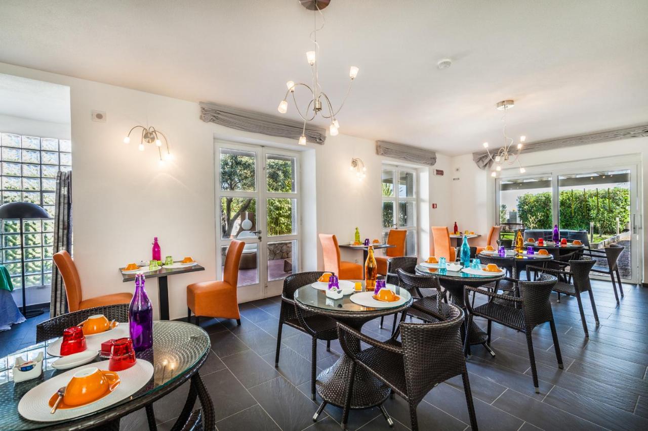 een eetkamer met tafels en stoelen en ramen bij Hotel Residence Hibiscus in La Caletta