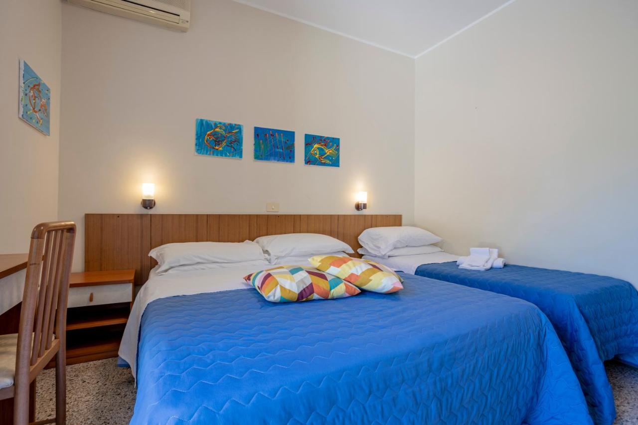 een slaapkamer met twee bedden met blauwe lakens en kussens bij Hotel Stella Del Mare in Cervia