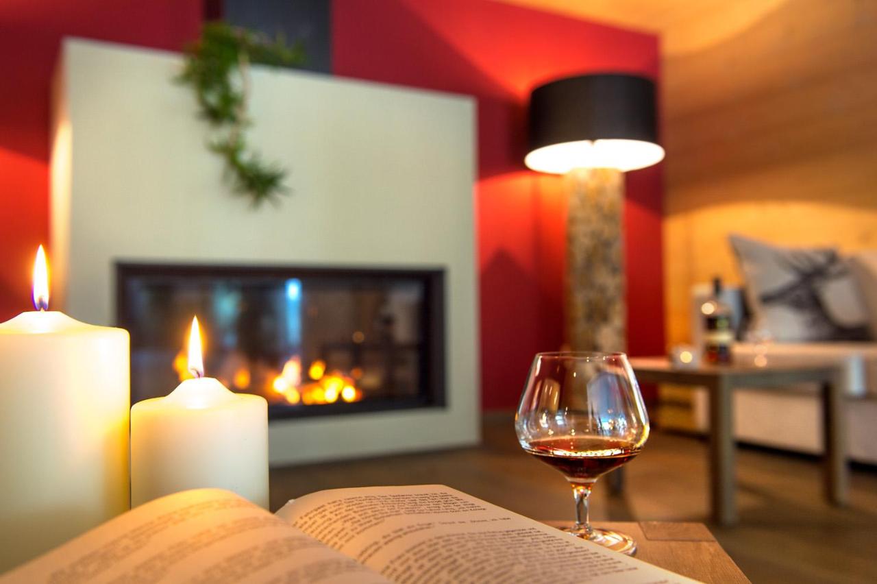 Een open boek en een glas wijn op een tafel met kaarsen. bij Hotel Regglbergerhof in Nova Ponente