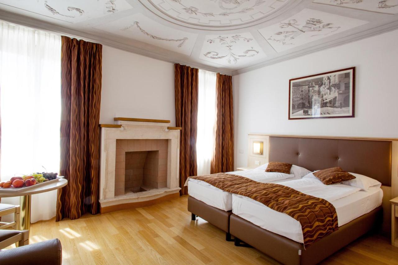 een slaapkamer met een groot bed en een open haard bij Hotel Portici - Romantik & Wellness in Riva del Garda