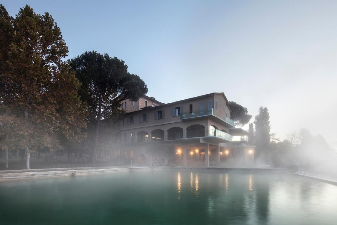 een gebouw in de mist naast een waterplas bij La Posta Hotel & Thermal Spa - Adults Only in Bagno Vignoni