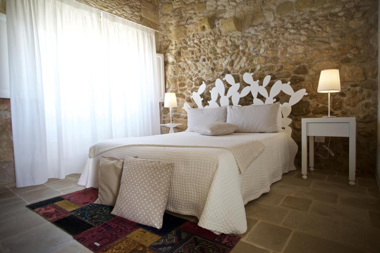 een slaapkamer met een groot wit bed en een stenen muur bij Don Agostino Relais Masseria in Martano