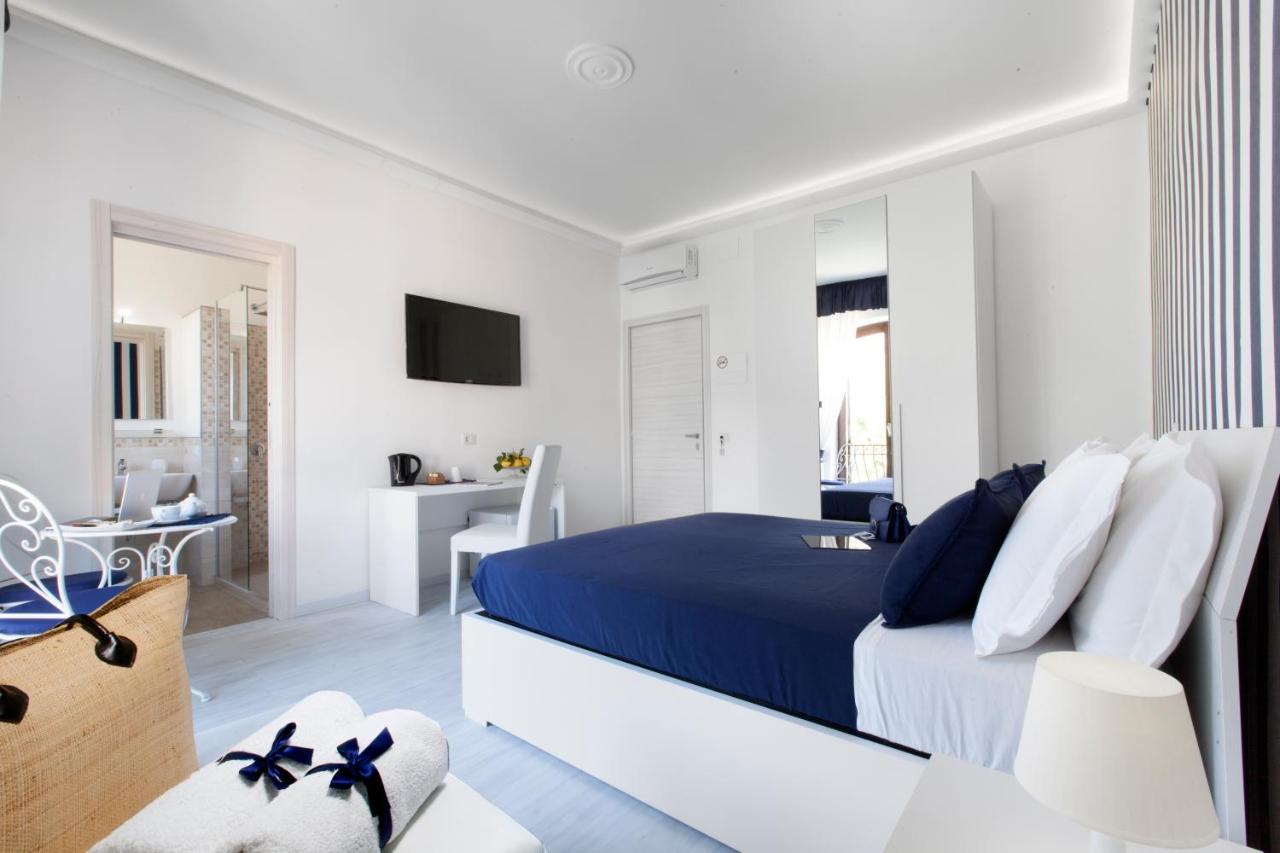 een witte slaapkamer met een blauw bed en een bureau bij Villa Iolanda in Piano di Sorrento