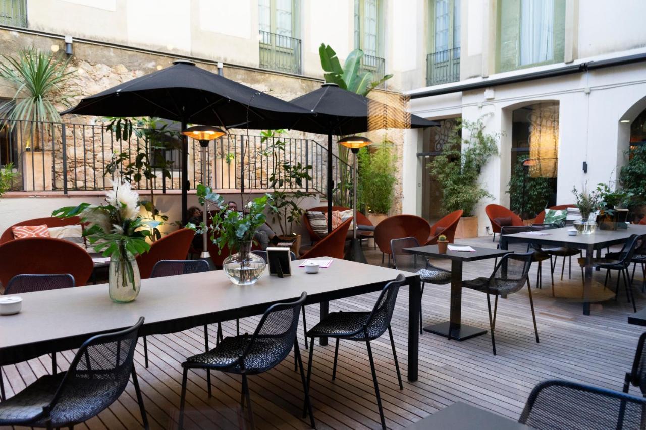 een terras met tafels en stoelen en een parasol bij Petit Palace Boqueria Garden in Barcelona