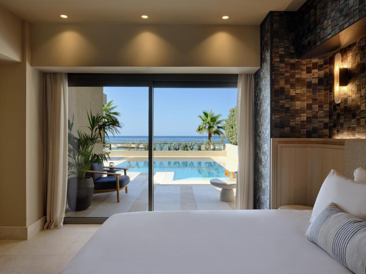 een slaapkamer met een bed en uitzicht op de oceaan bij Atlantica Kalliston Resort - Adults Only in Stalós
