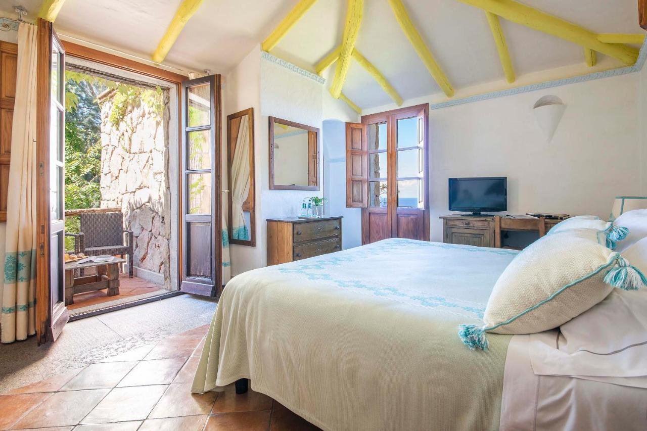 een slaapkamer met een groot bed en een televisie bij Hotel Monte Turri by Falkensteiner in Àrbatax