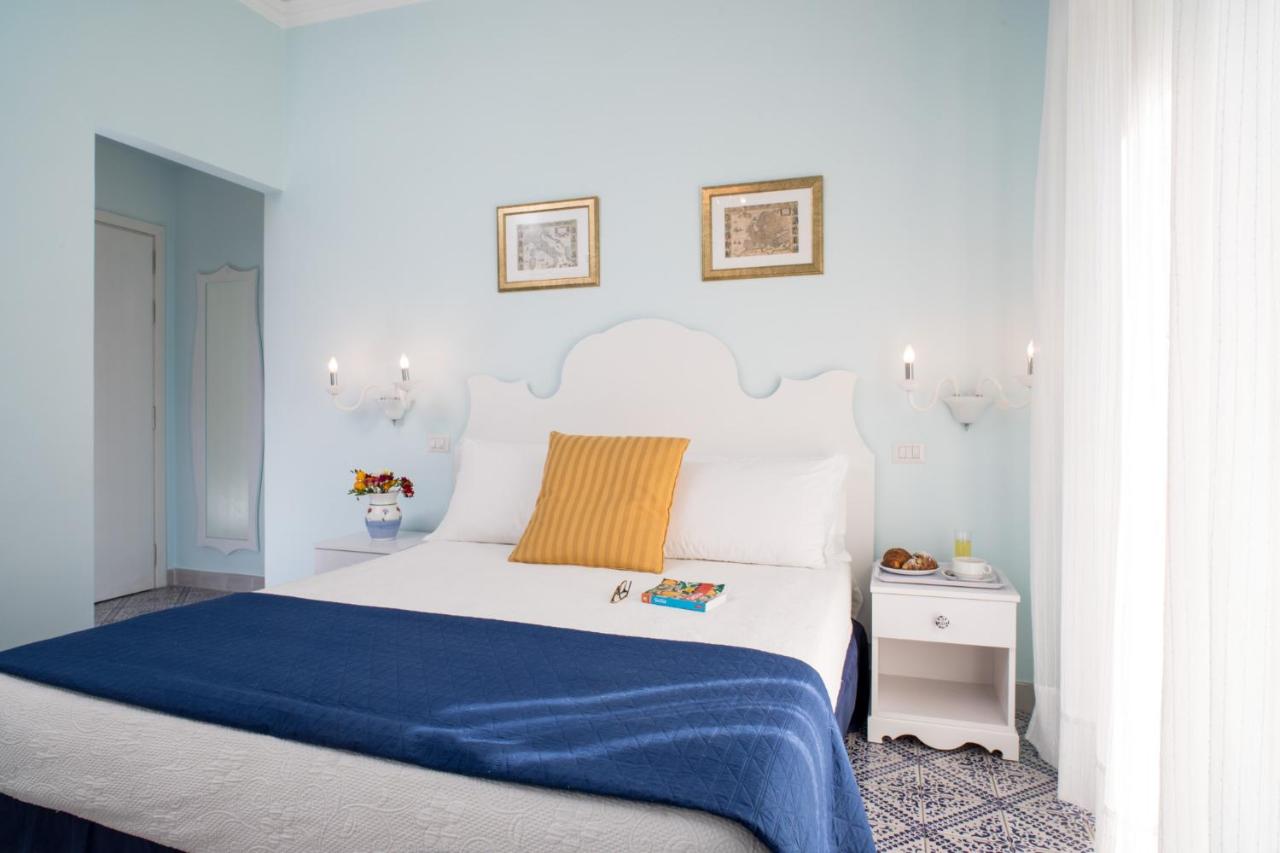 een slaapkamer met een wit bed en een blauwe deken bij Hotel Villa Nefele in Giardini Naxos