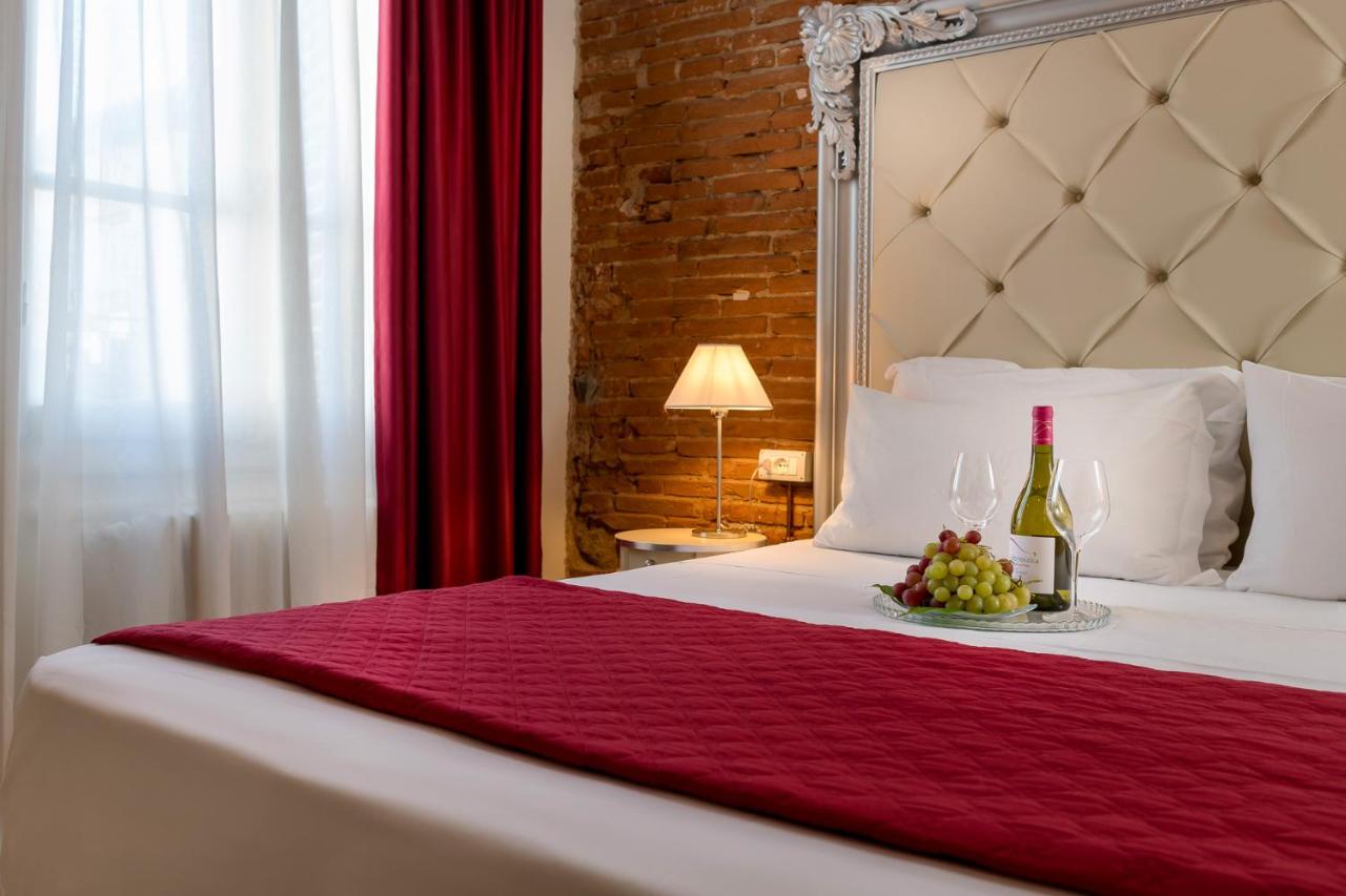 een bed met een fles wijn en een schaal druiven bij Residenza Conte di Cavour & Rooftop - dBe Hotels in Florence