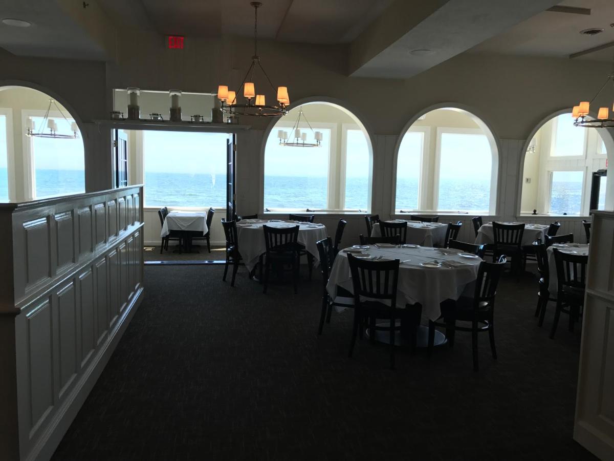 een eetkamer met tafels en stoelen en ramen bij The Three Seasons Resort in Dennis Port