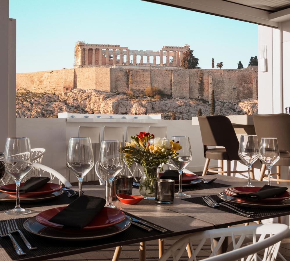 een eettafel met wijnglazen en uitzicht op een gebouw bij Acropolis Select in Athene