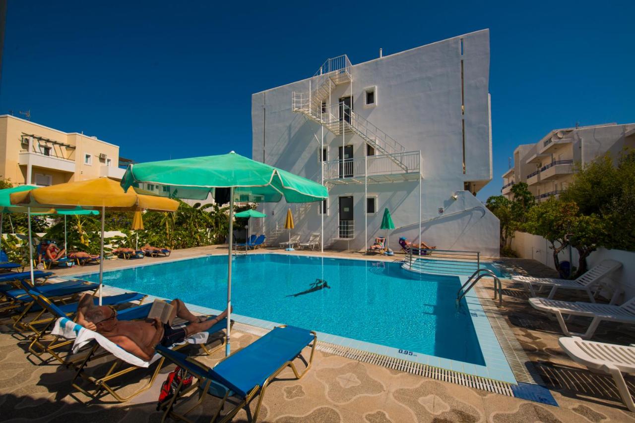 een zwembad met stoelen en parasols naast een gebouw bij International Hotel in Kos-stad