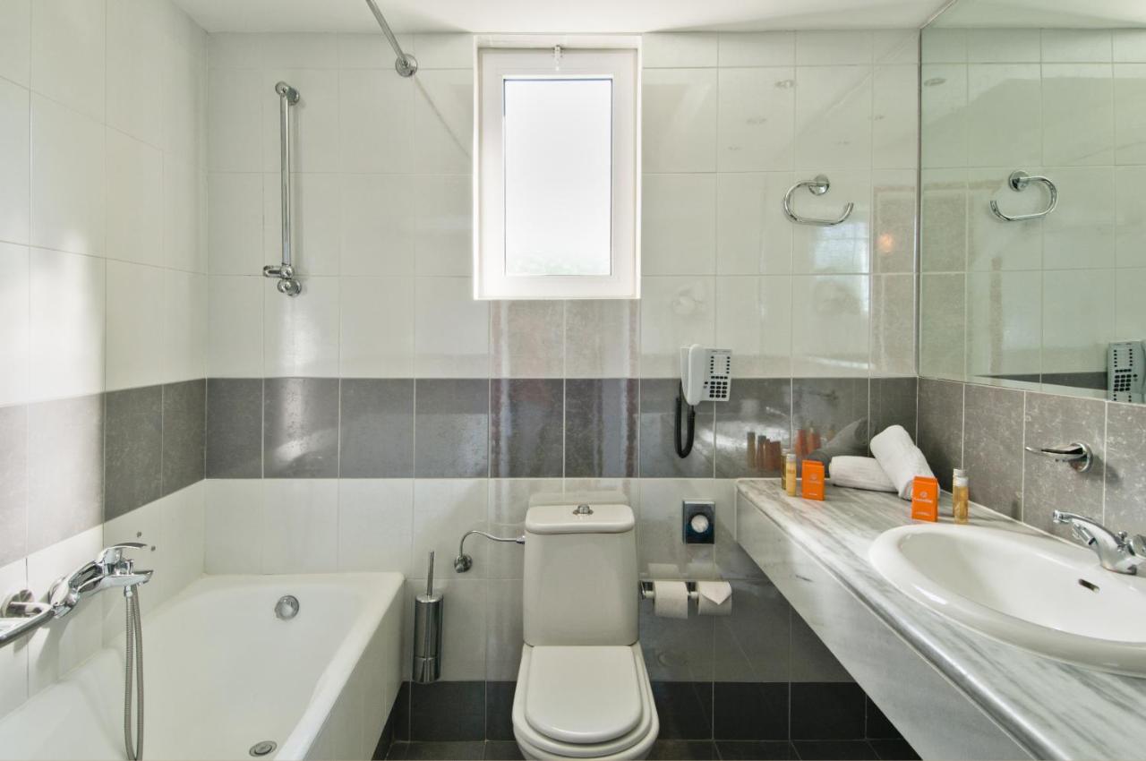 een badkamer met een wastafel, een toilet en een badkuip bij Kipriotis Village Resort by Anayia All Inclusive Resorts in