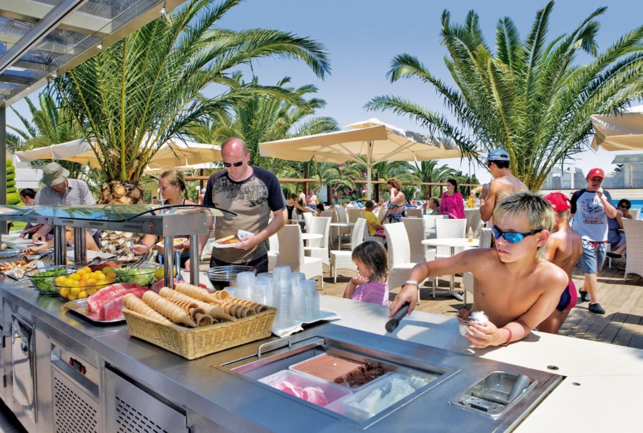een man die eten klaarmaakt bij een buffet in een resort bij Kipriotis Village Resort by Anayia All Inclusive Resorts in
