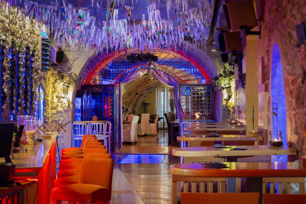 een restaurant met een bar met oranje stoelen en een kroonluchter bij Avli Lounge Apartments in Rethimnon