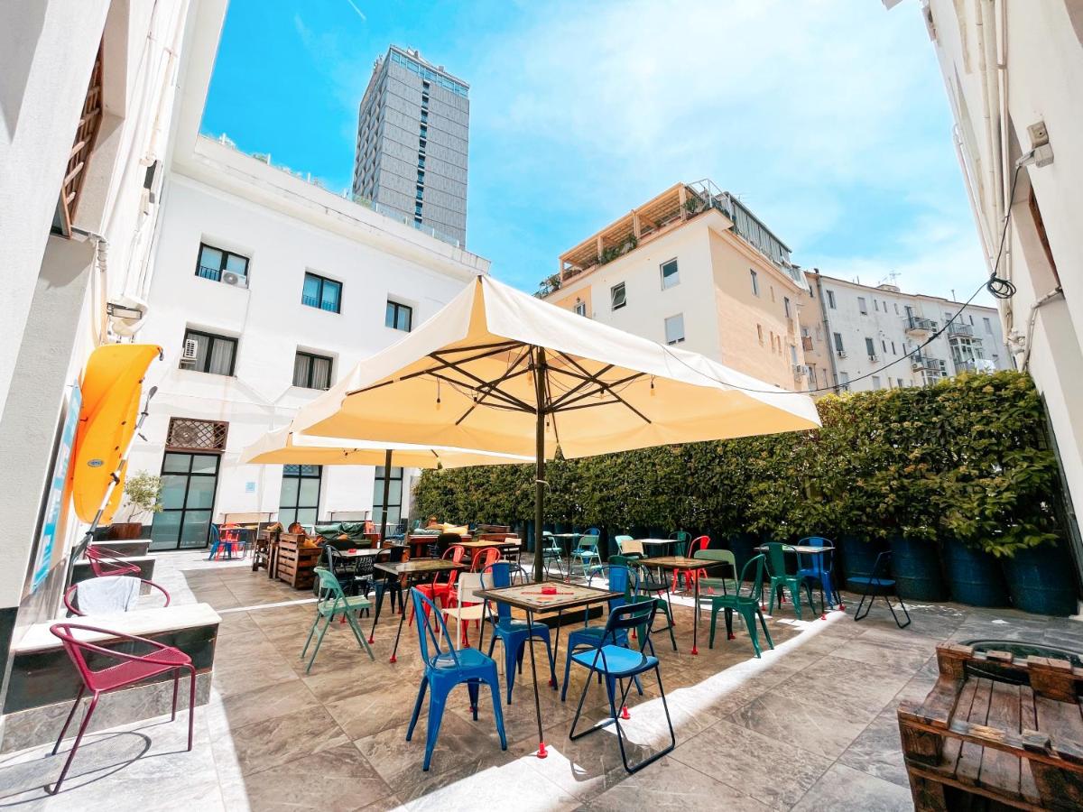 een terras met tafels en stoelen en een parasol bij Ostello Bello Napoli in Napels