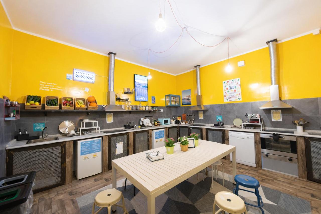 een keuken met gele muren en een tafel en stoelen bij Ostello Bello Napoli in Napels
