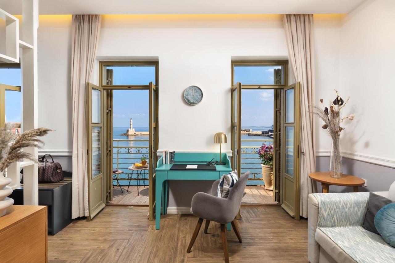 een woonkamer met een bureau en uitzicht op de oceaan bij Elia Palatino Hotel in Chania