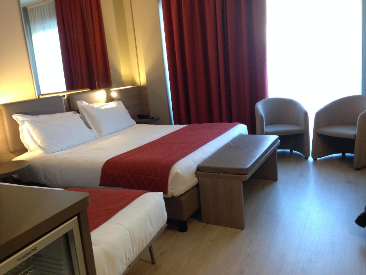 een hotelkamer met twee bedden en een tv bij Cardano Hotel Malpensa in Cardano al Campo
