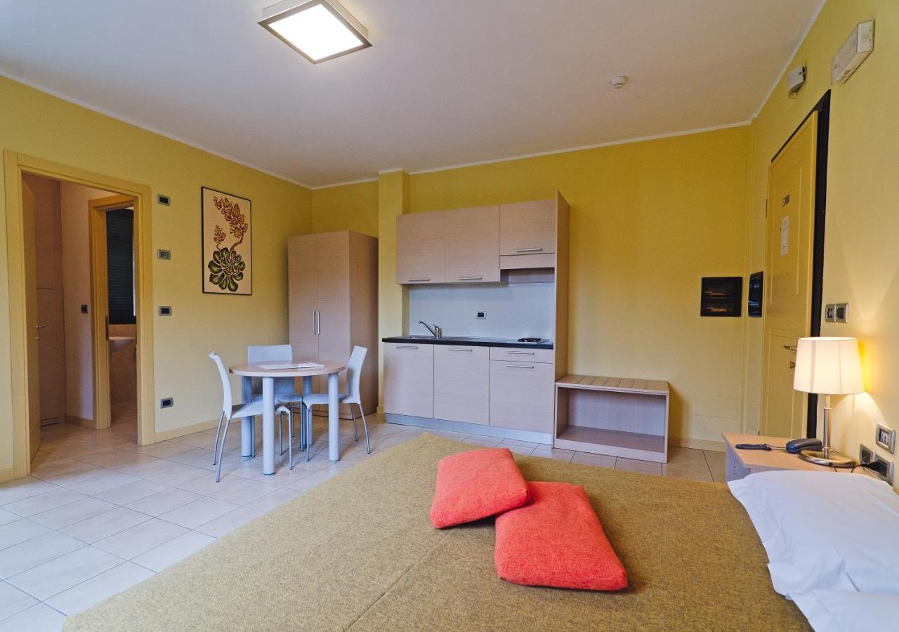 een woonkamer met een keuken en een tafel met rode kussens bij Castellaro Golf Resort in Castellaro