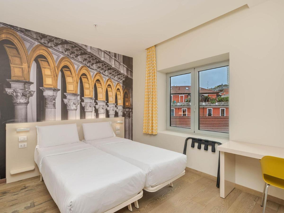 een slaapkamer met een wit bed, een bureau en ramen bij B&B Hotel Milano Central Station in Milaan