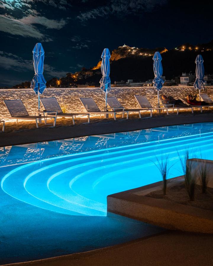een zwembad met blauwe parasols 's nachts bij Airotel Alexandros in Athene