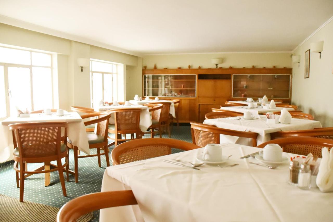 een eetkamer met tafels en stoelen met een wit tafelkleed bij Adrian Hotel in Athene