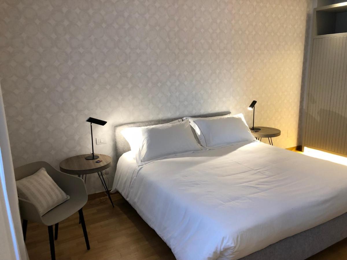een slaapkamer met een wit bed, twee tafels en een stoel bij 200 ROOMS & TERRACE in Bari