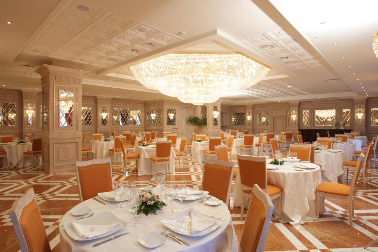 een feestzaal met witte tafels en stoelen en een kroonluchter bij Grand Hotel Vanvitelli in Caserta