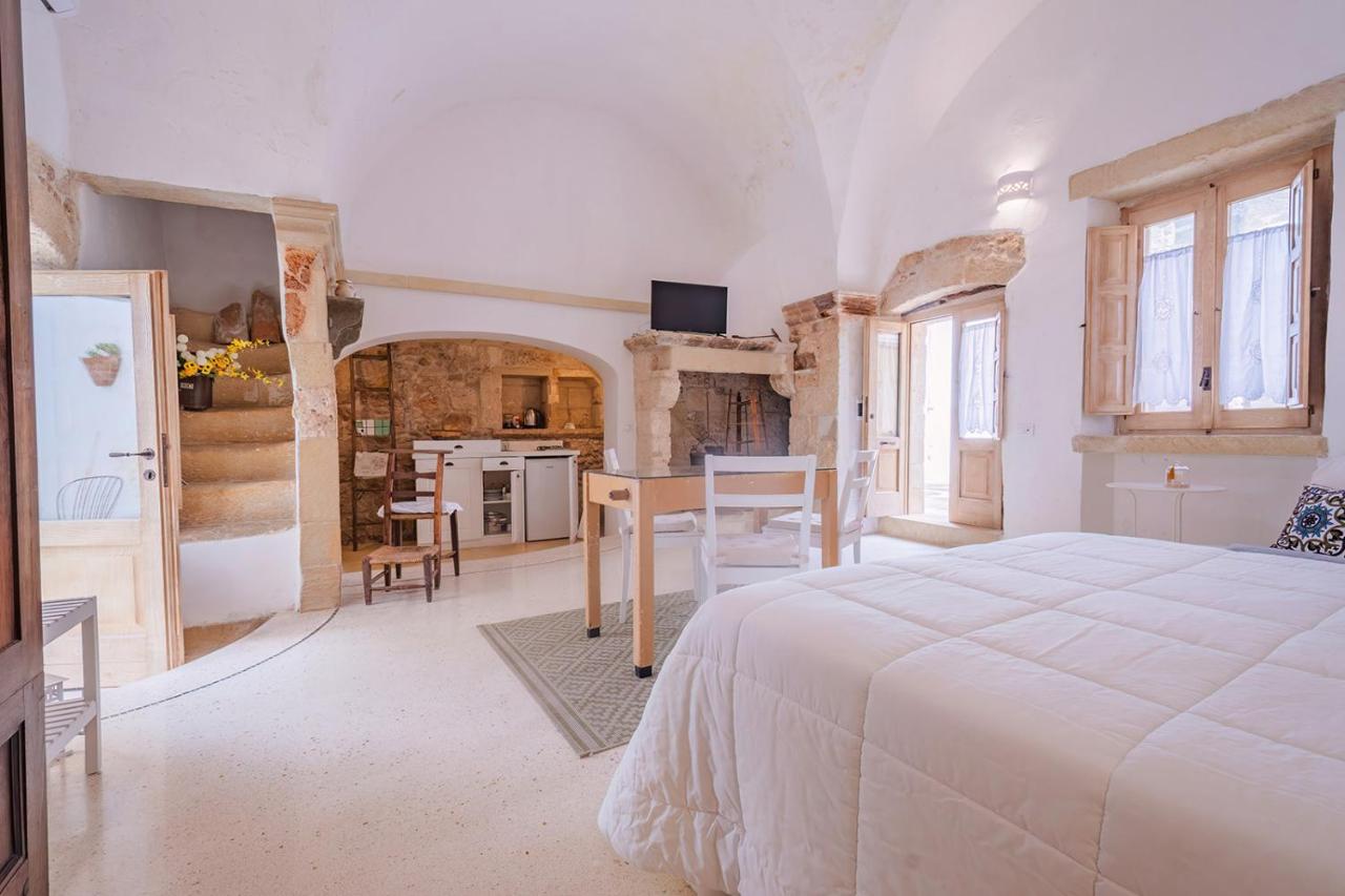 een slaapkamer met een wit bed en een keuken bij HISTORIA- Dimore Corte Chiesa in Corigliano dʼOtranto