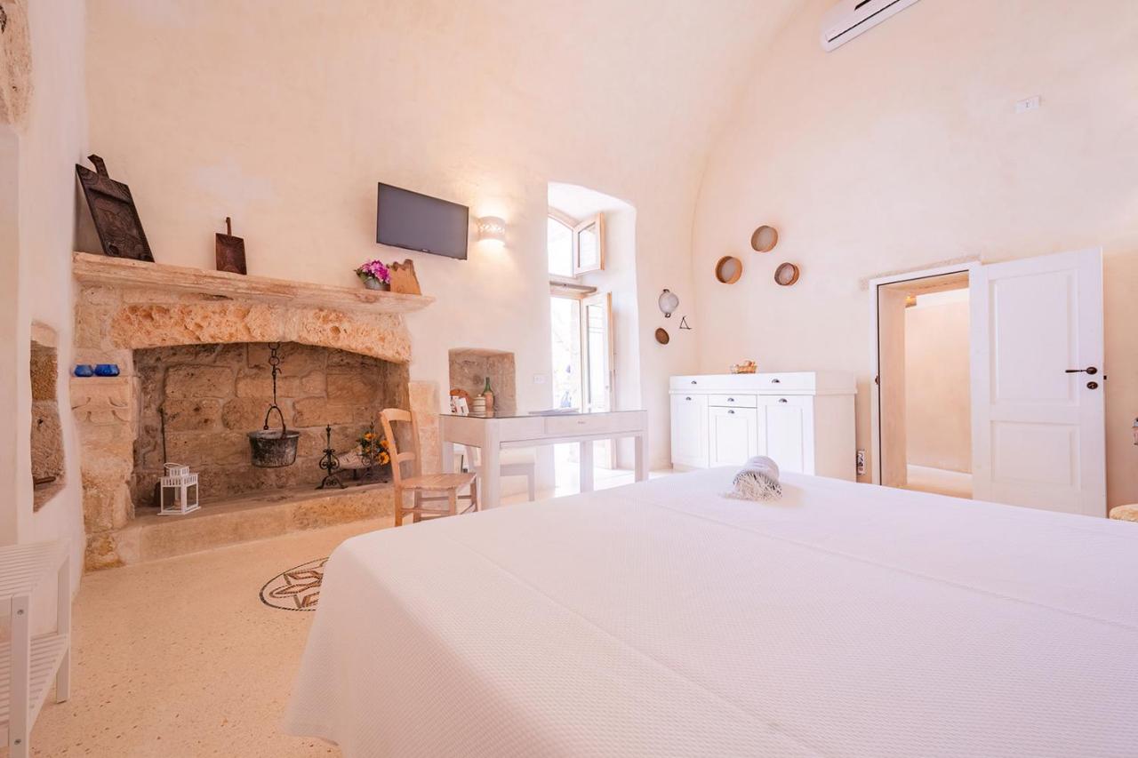 een slaapkamer met een wit bed en een open haard bij HISTORIA- Dimore Corte Chiesa in Corigliano dʼOtranto
