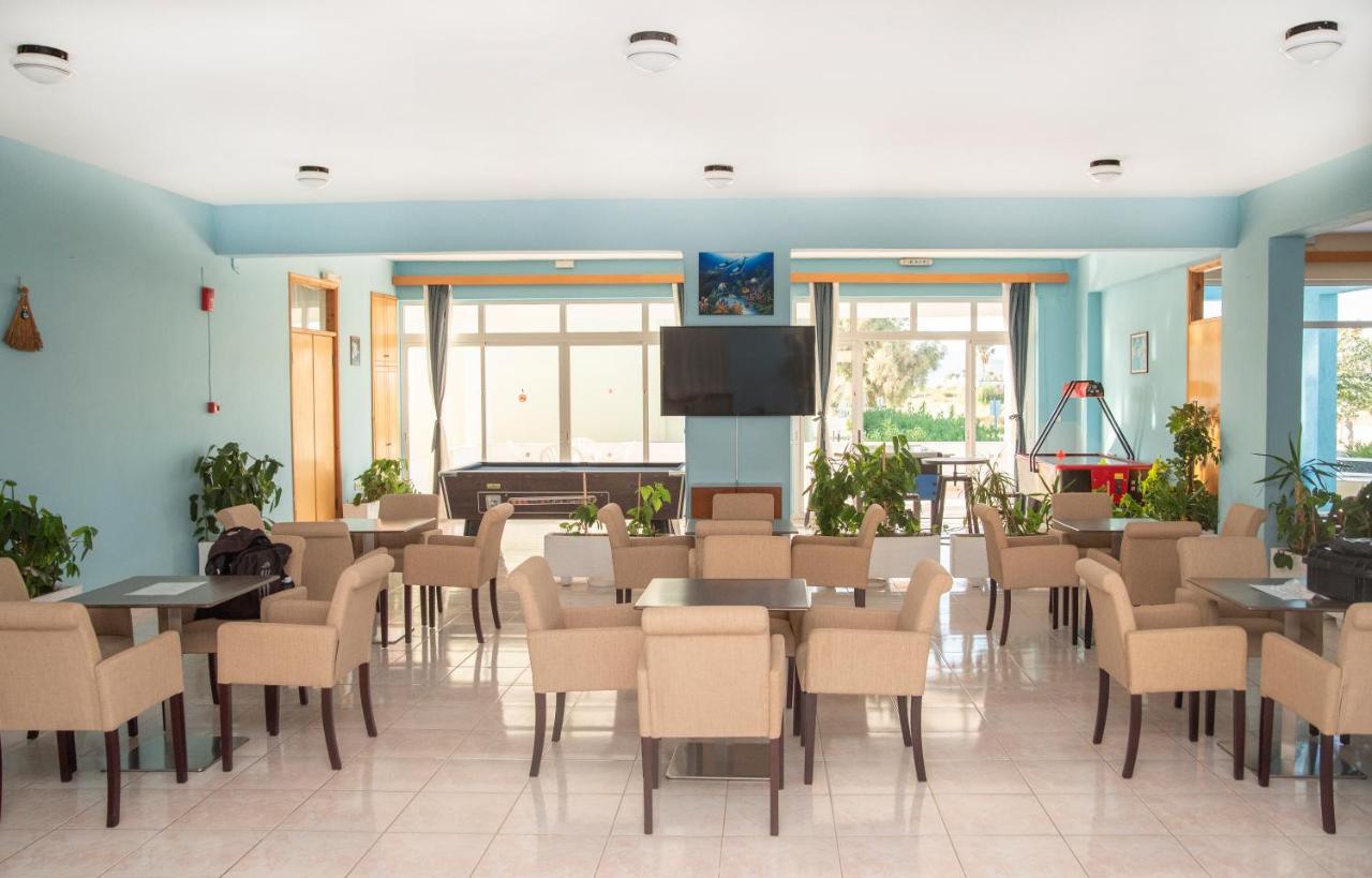 een wachtkamer met tafels en stoelen en een flatscreen-tv bij Oasis Tigaki in Tigaki