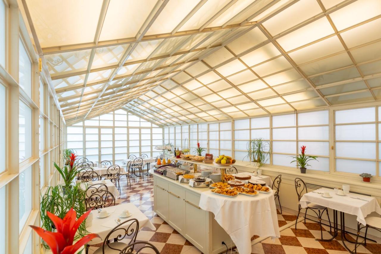 een grote kamer met tafels en stoelen en ramen bij Hotel Giudecca Venezia in Venetië