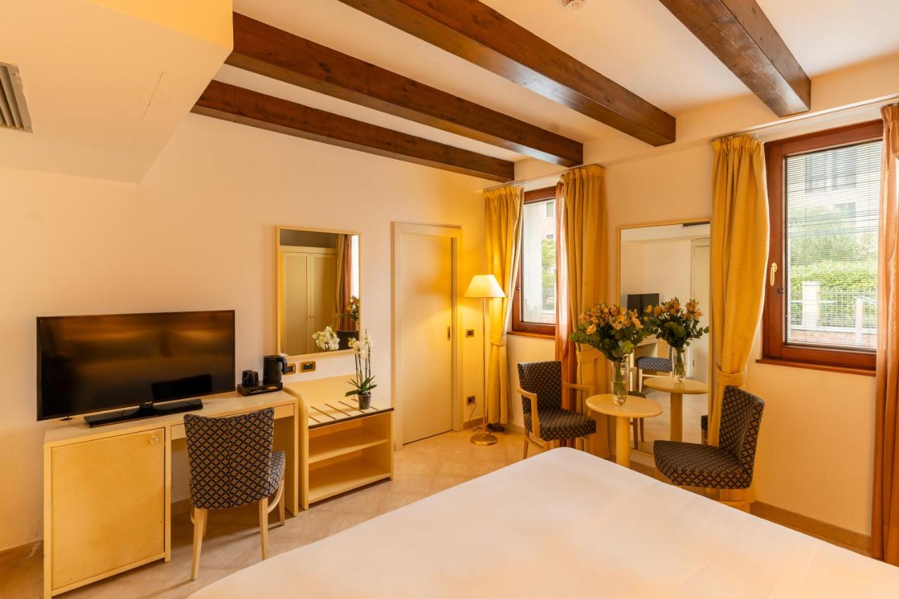een woonkamer met een televisie, een tafel en stoelen bij Hotel Giudecca Venezia in Venetië