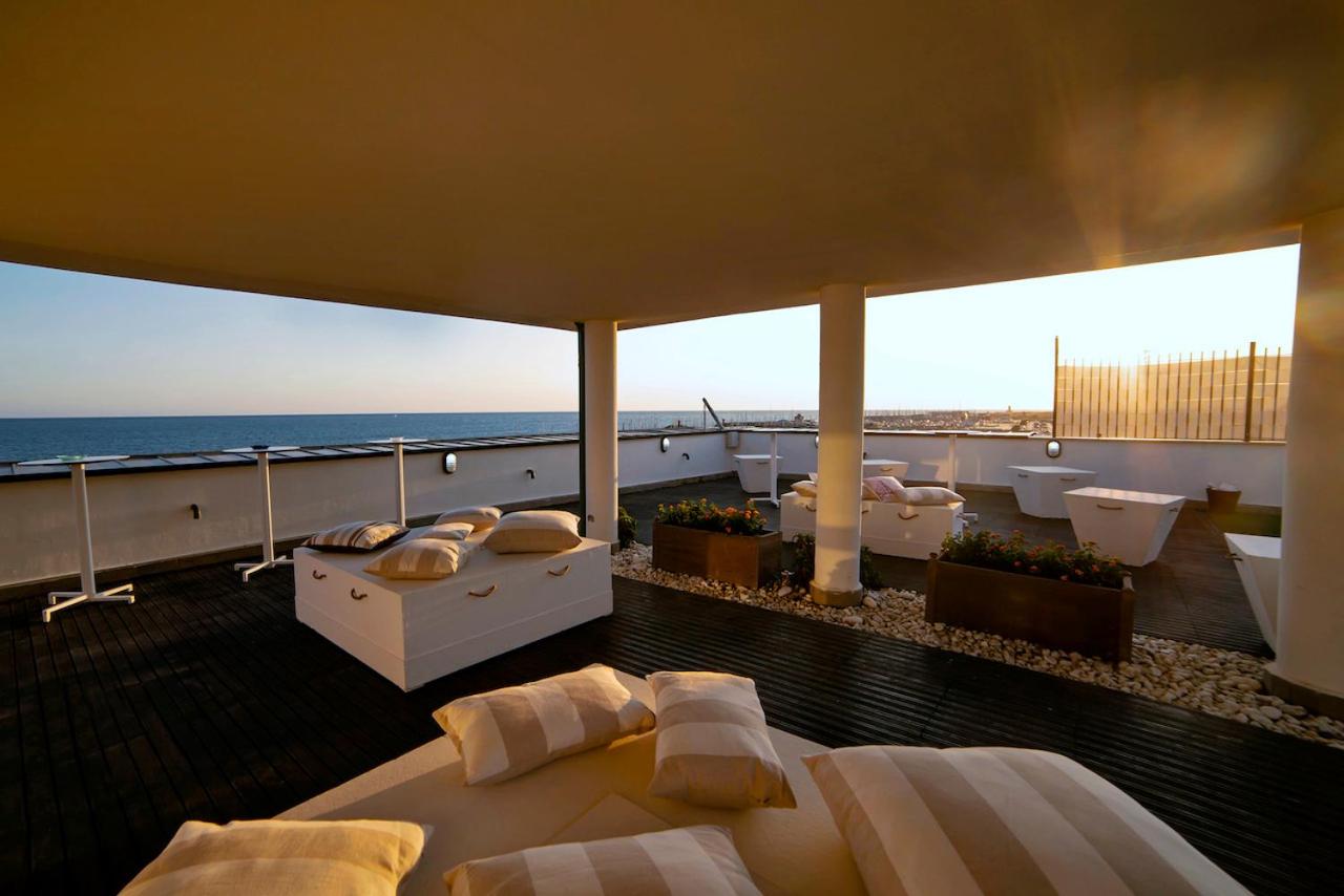 een kamer met bedden en een balkon met uitzicht op de oceaan bij Smy Aran Blu Roma Mare in Lido di Ostia