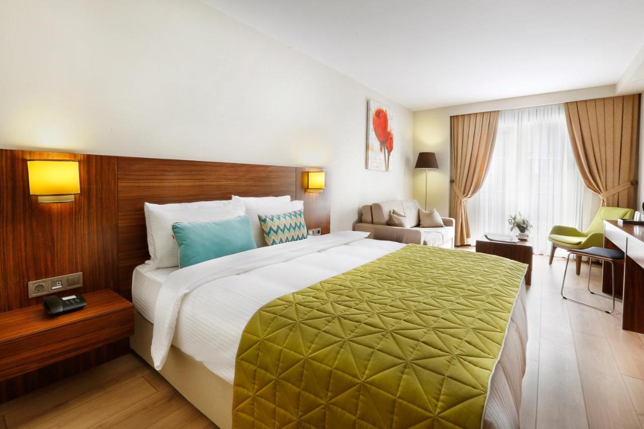 een hotelkamer met een groot bed met een groene deken bij The White Orient Hotel in Istanbul