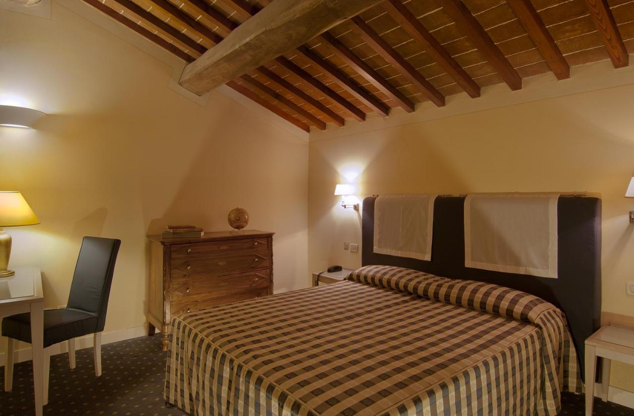 een slaapkamer met een bed, een stoel en een bureau bij Hotel Arnolfo & Aqua Laetitia Spa & Beauty in Montecatini Terme