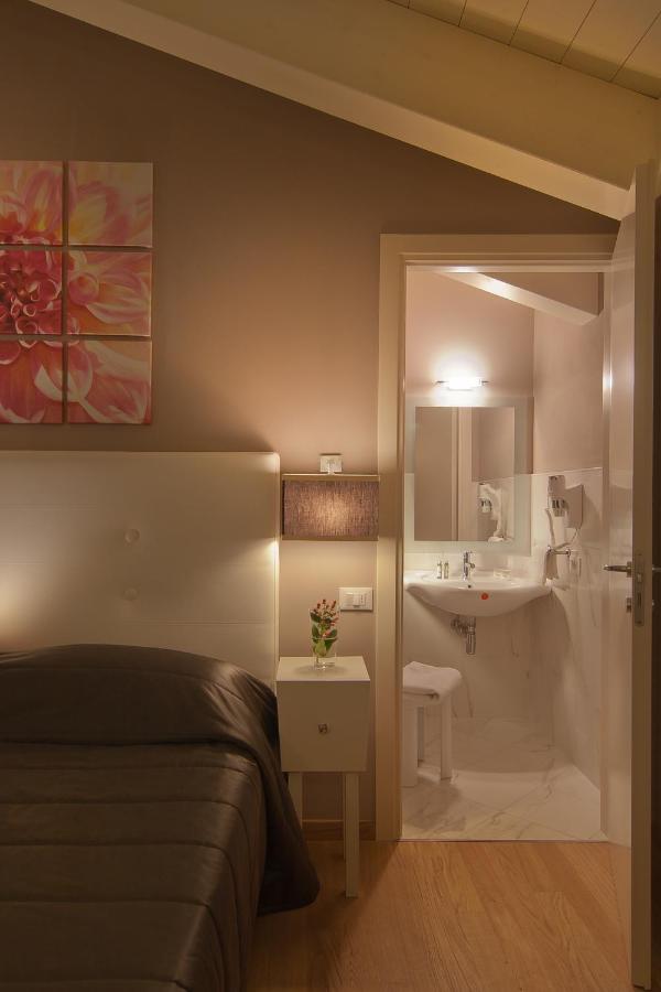 een slaapkamer met een bed en een badkamer met een wastafel bij Hotel Arnolfo & Aqua Laetitia Spa & Beauty in Montecatin