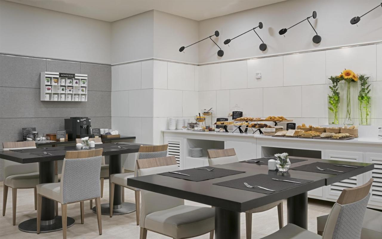 een eetkamer met tafels en stoelen en een toonbank bij NH Ciudad Real in Ciudad Real