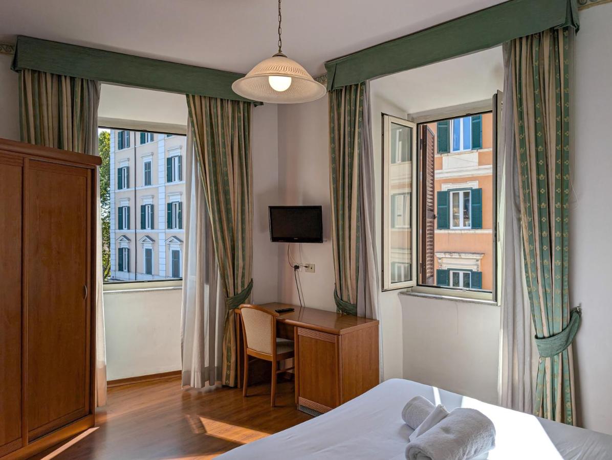 een slaapkamer met een bed, een bureau en twee ramen bij Hotel Philia in Rome