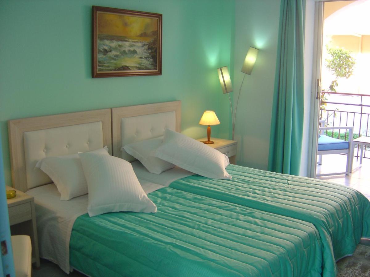een slaapkamer met een bed met een groen dekbed bij Roda Pearl Resort in Roda