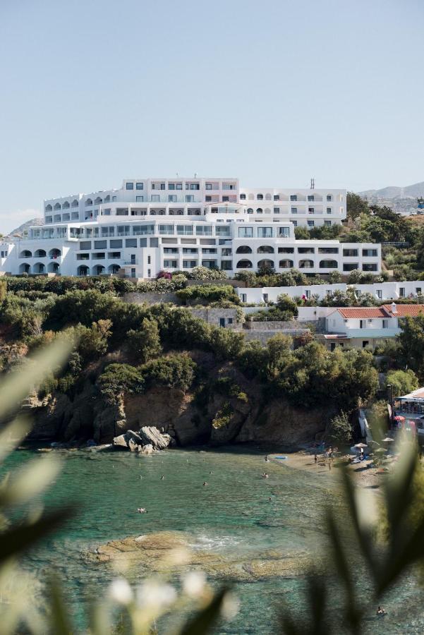 een groot wit gebouw op een heuvel naast een strand bij Peninsula Resort & Spa in Agia Pelagia
