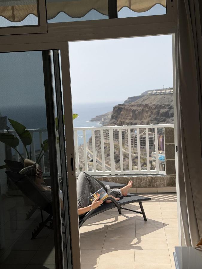 Een persoon die in een stoel op een balkon ligt en een boek leest. bij AMADORES BEACH VIEW APARTMENT in Amadores