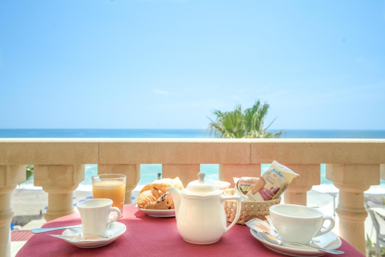 een tafel met kopjes en borden met eten op een balkon bij Hotel Orizzonte in Letojanni