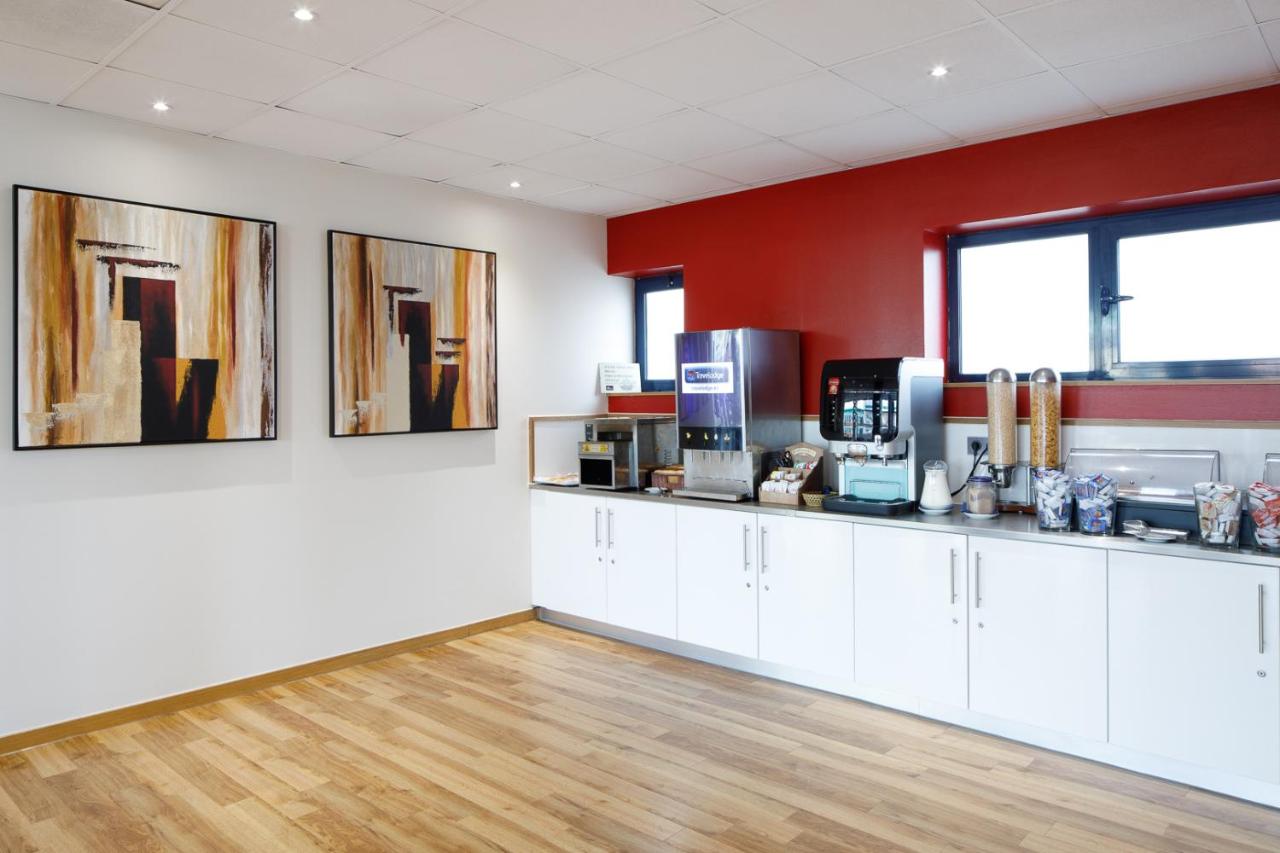 een keuken met witte kasten en een rode muur bij Travelodge Barcelona Fira in Hospitalet de Llobregat