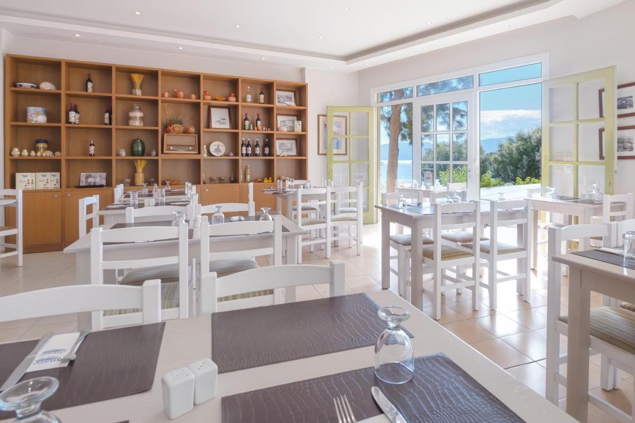 een restaurant met witte tafels en stoelen en een groot raam bij Mare Hotel Apartments in Agios Nikolaos